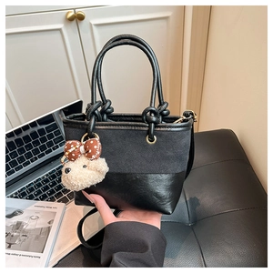Detail of black crossbody bucket bag with suede texture and cute teddy bear charm
