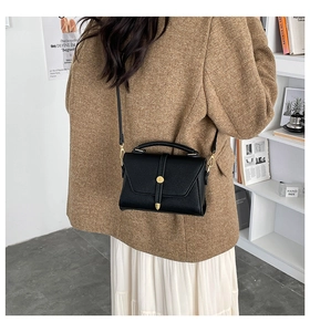 Close-up of black litchi pattern leather small square bag with golden hardware
