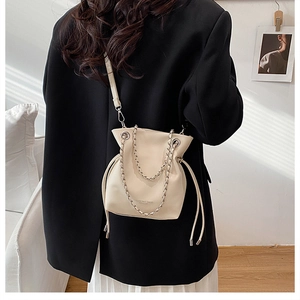 Detail of beige bucket bag featuring drawstring closure and stylish chain shoulder strap