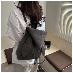 Close-up of suede backpack featuring 3D rabbit ear design and drawstring closure