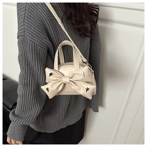 Detail view of the beige bow bag featuring silver star studs worn over the shoulder