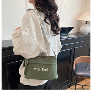 Detail of dark green corduroy crossbody bag with TOTE BAG embroidery and geometric strap