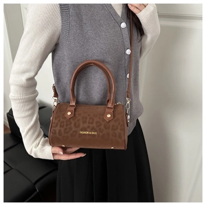 Detail of leopard print cylinder bag with gold metal hardware and adjustable strap