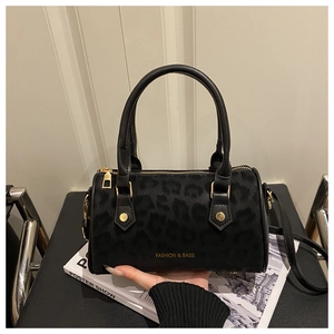 Detail view of black leopard print Boston bag with gold zippers and detachable strap