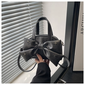 Close-up of black PU leather handbag with large bow and silver star rivets detail