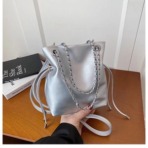 Detail of silver bucket bag with metallic drawstring closure and chain shoulder strap
