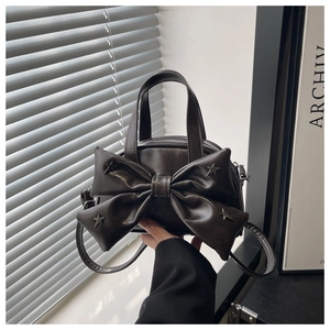 Detail of dark brown leather bucket bag with oversized bow and silver star studs