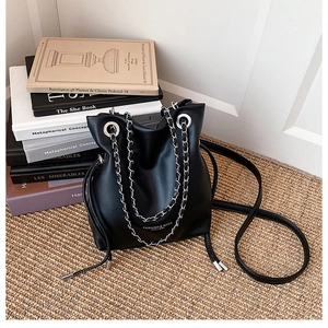 Detail of black leather bucket bag with silver chain handles and fashion typography