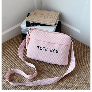 Detailed shot of pink corduroy tote bag with embroidered logo and woven shoulder strap