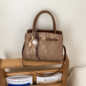 Detail of vintage brown PU tote with vertical texture and baseball bat charm ornament