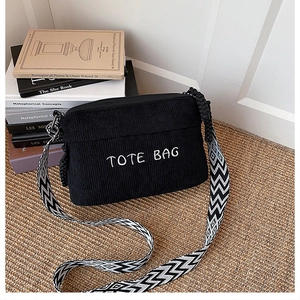 Detail of black corduroy small square bag with TOTE BAG embroidery and wide strap