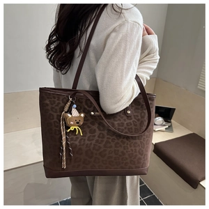 Détail d'un grand sac fourre-tout léopard avec logo doré et pendentif d'ours