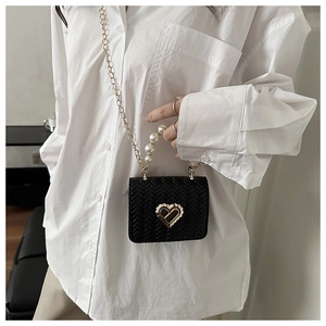 Detail of black woven crossbody bag with pearl handle and golden heart lock