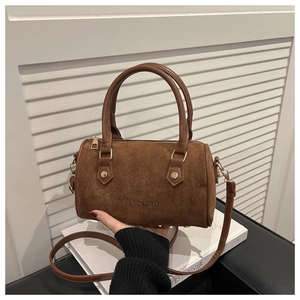 Detailed close-up of brown suede Boston bag featuring embossed logo and golden hardware