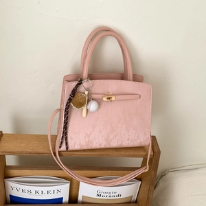 Close-up of pink textured PU leather tote bag featuring metal clasp and sports theme charm