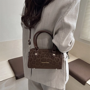 Chic leopard print Boston bag with brown handles and gold lettering shown cross-body