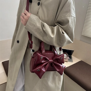 Deep red leather crossbody bag featuring a large bow and silver star studs on front