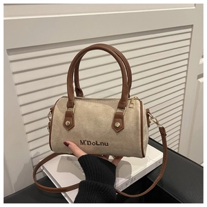Close-up of beige suede Boston bag with brown leather trim and golden metal hardware