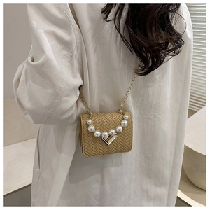 Detail of khaki woven crossbody bag with pearl decoration and golden heart lock