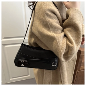 Detail of a black matte leather underarm bag featuring silver buckle and cross strap design