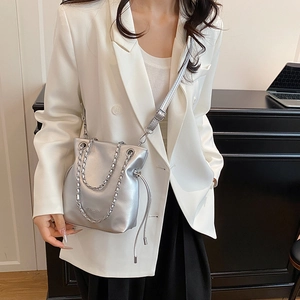 Silver metallic bucket bag with chain handle and adjustable strap for women in a modern setting