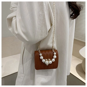 Detail of woven straw handbag with decorative pearl handle and gold chain strap