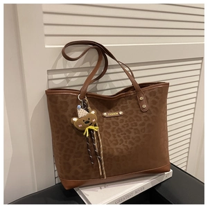 Détail du sac seau à imprimé léopard avec plaque dorée et breloque ours peluche