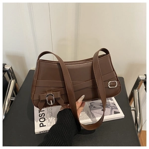 Detail of dark brown baguette bag featuring lace-up straps and a leather bow detail