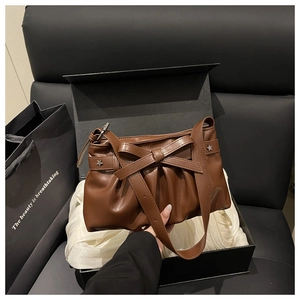 Détail d'un sac en cuir marron vintage avec nœud et rivets étoiles dans une boîte cadeau