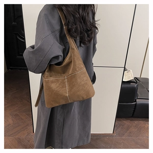 Detail view of large brown tote bag with contrast white stitching on premium matte leather