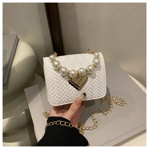 Close-up of white woven bag with pearl handle and golden heart-shaped metal lock