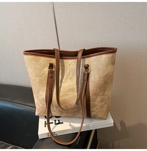 Dettaglio macro della borsa tote in tela giallo senape con finiture in pelle su divano