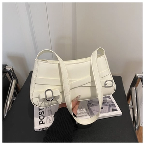 Detail of minimalist white underarm bag with decorative cross straps and silver buckles