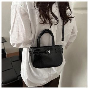 Détail d'un mini sac à main chic en cuir brillant noir avec boucle en métal argenté
