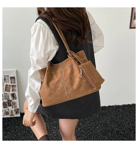 Close-up of brown suede tote bag with contrast stitching and matching mini pouch bag