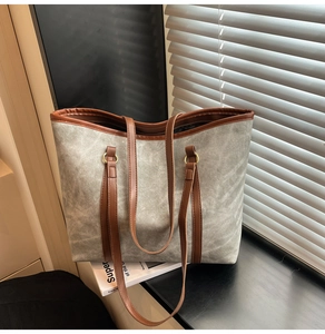 Dettaglio della borsa tote in tela con texture grigia e cinturino in pelle marrone