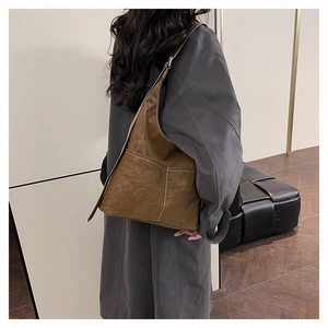 Close-up of retro brown frosted tote bag showing textured synthetic leather and white stitching