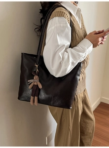 Detail of deep brown faux leather tote bag with a cute plush bunny charm hanging on it