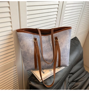 Dettaglio della borsa tote in tela blu con finiture in pelle marrone e anelli dorati