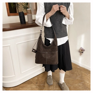 Detail of dark brown tote bag featuring white contrast stitching and soft matte texture