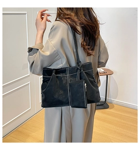 Detail of black leather tote bag with white contrast stitching and mini pouch