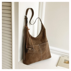 Detail of a dark brown suede Hobo tote bag with white contrast stitching and a mini pouch