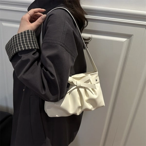 Sac à bandoulière plissé blanc crème chic avec nœud et étoile porté par un mannequin