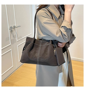Detail of dark brown faux leather tote with white contrast stitching and shoulder strap