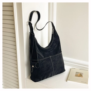Detail of black matte hobo bag with contrast white stitching and side pocket features