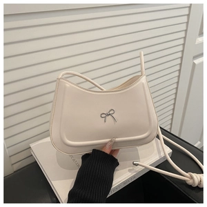 Dettaglio di una borsa a tracolla bianco crema con fiocco in metallo e tracolla a nodo
