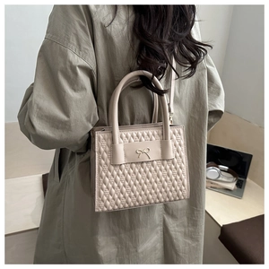 Détail du sac à main carré beige avec motif matelassé et nœud en métal sur la bandoulière