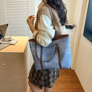 Borsa tote in tela blu con finiture in pelle marrone indossata a spalla per stile casual