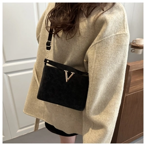 Détail du sac bandoulière en daim noir avec boucle dorée en V et sangle réglable