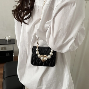 Elegant black woven crossbody bag with pearl heart detail and gold chain strap